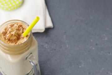 Iced Dalgona Coffee, a trendy fluffy creamy whipped coffee. Glass mug, cotton napkin close-up on a gray background. Horizontal position. Copy space.
