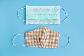 Medical mask and handmade cotton fabric face mask on color background to protection against pollution, flu and Corona virus. Disposable face mask cover mouth and nose. Health care concept. Top view