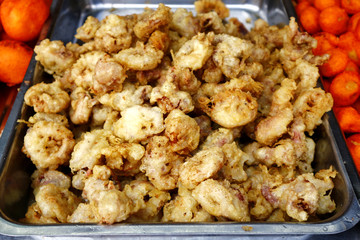 Assorted deep fried street food sold at a food cart along a sidewalk.