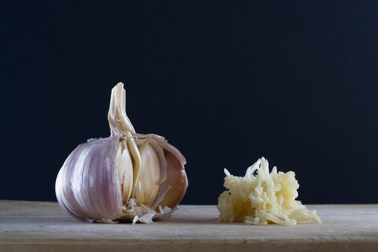 A head of garlic and a pressed garlic against black background