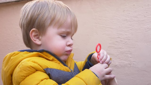 blond boy learning to blow soap bubbles on the terrace of his house