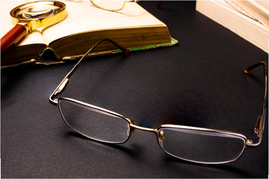 Books with glasses on black table and wooden background. High resolution image depicting reading/bokks industry.