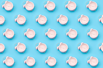 Nostalgia repetitive wallpaper and passing of time concert with minimalist seamless pattern layout of pastel pink mechanical alarm clock isolated on vibrant blue background