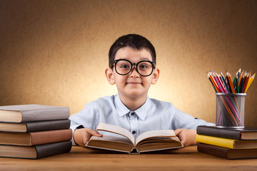 cute little boy schoolboy doing homework at a table with books. education. Junior School