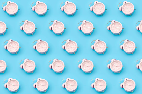 Nostalgia repetitive wallpaper and passing of time concert with minimalist seamless pattern layout of pastel pink mechanical alarm clock isolated on vibrant blue background