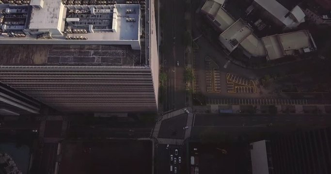 Bird's eyes view aerial flight over avenue tilting up to reveal urban city. Drone, 4K.