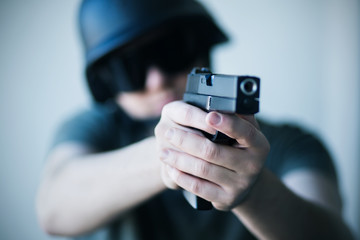 A man in a helmet and protective black glasses holds a gun in his hands and takes aim. Police. Army. Crime.