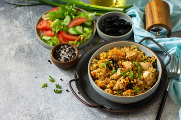 Bulgur pilaf. Healthy eating concept. Bulgur with chicken, vegetables and prunes on a gray stone or...