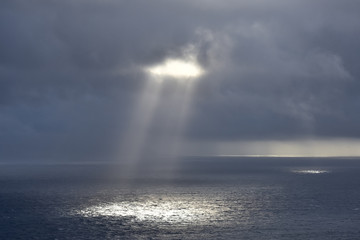 Rays of light that pass over the clouds and illuminate the sea like spotlights. Concept of nature and sea. Galicia, Spain