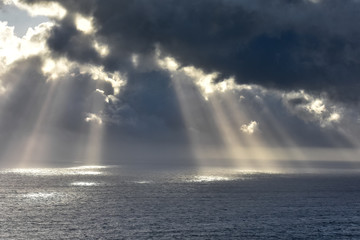 Naklejka premium Rays of light that pass over the clouds and illuminate the sea like spotlights. Concept of nature and sea. Galicia, Spain