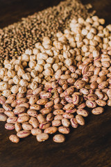 Mix of raw grains: lentils, chickpeas, brown and white beans  on the wooden table