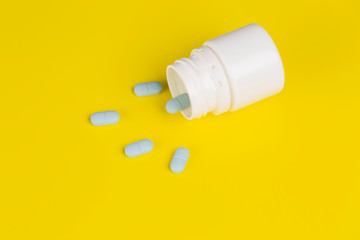 Different medications. White pill bottle. One-color backdrop.