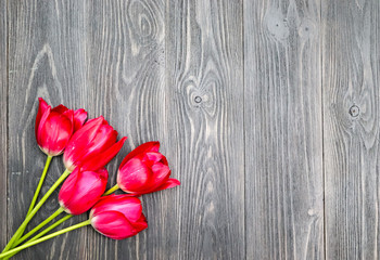Fototapeta na wymiar Dark wooden background with place for an inscription and red tulips.