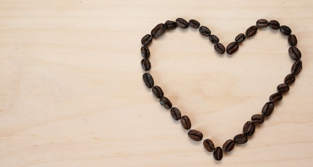 The shape of the heart is laid out on a light background of roasted coffee beans, there is room for text.