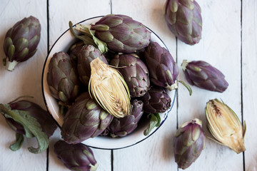 Fresh uncooked artichokes vegetables in a white bowl, healthy food