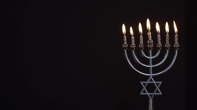 View of Menorah With All Candles Burning on Black Background