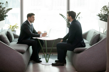 Job interview, client and company representative meeting, colleagues talking solving current business issues concept. Two caucasian businessmen in suits sitting opposite each other in modern office