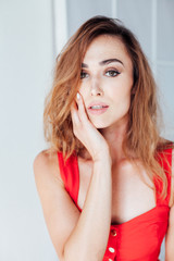 Fototapeta premium Portrait of a beautiful red woman in a red business dress at work in the office