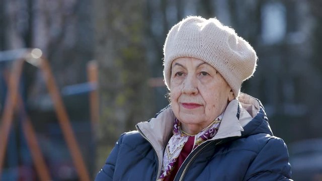 A pensive lonely old woman is in deep thought, looking away sitting alone on blurry background. Beautiful woman 81 years old.