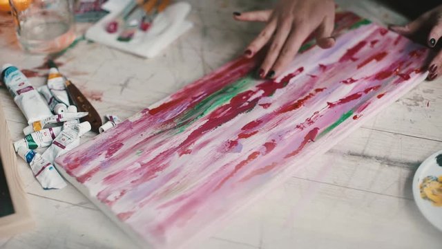 girl artist fingers paints a picture on canvas in the studio