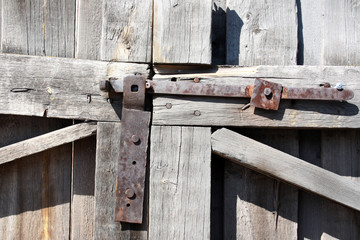 Metal rusty latch on a wooden gate. Fragment of the old gate.
