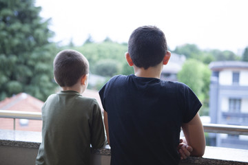 Two brothers children look out of them prison home during coronavirus pandemy
