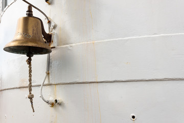 Obraz premium Brass ship's bell on the exterior of a fire fighter boat, white painted metal, copy space, horizontal aspect