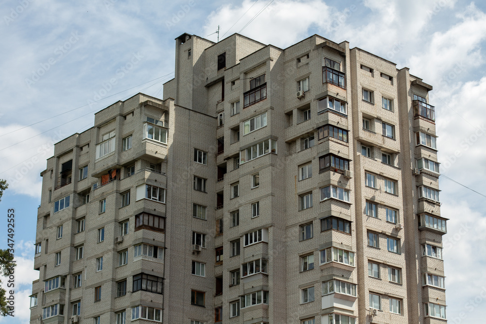 Wall mural tall apartment building against the sky and clouds