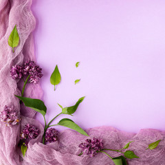 lilac flowers and leaves on a pink-lilac background with fabric drapery. flat lay, copy space.