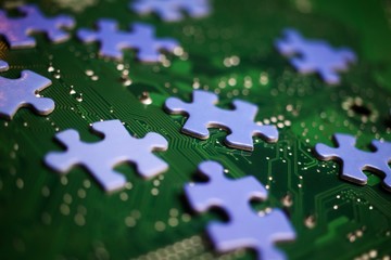 Central personal anonymous data storage and collection concept: Close up of blue shattered puzzle pieces on green computer mainboard