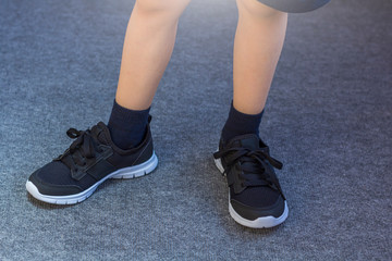 Young boy's legs in textile fashion black sneakers. Children's trendy casual outfit and street fashion. Top view, Close up