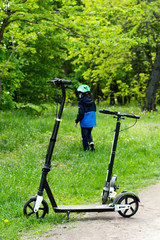 Fototapeta na wymiar child alone in the park on a scooter in a helmet