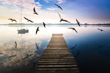 Birds fly over empty footbridge. The lake Selment Wielki, Masuria, Poland. - obrazy, fototapety, plakaty