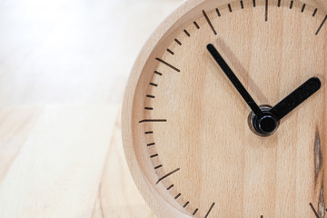 The close-up picture of the wooden table clock with a black dial showing about 2 o'clock on the...
