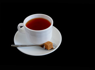 Herbal tea and pieces of brown sugar in a white mug on a black background. Suitable for advertising backgrounds and mockups