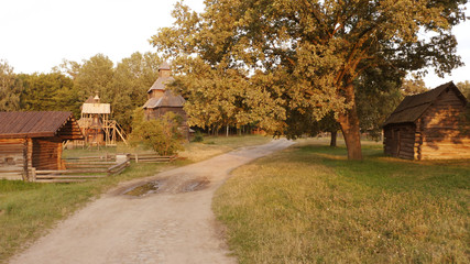 Sandy road in the village. Few log houses along the road.