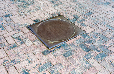 Rusty metal manhole cover on pavement road