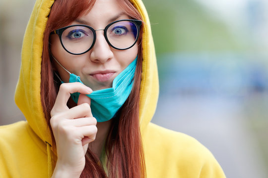 happy girl with glasses removes the medical mask from her face, shows a crazy look