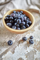 Image of blueberries in wooden bowl on rustic village table.