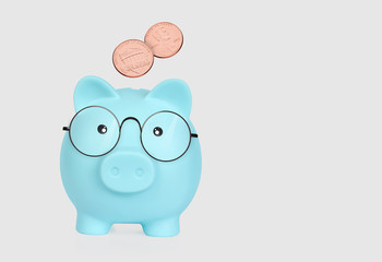 blue plastic piggy bank in glasses and cent coins isolated