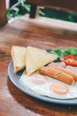 A Delicious healthy Homemade English or American breakfast and brunch - toast,fried egg sunny,bacon and vegetables  on a wooden table in restaurant. Flat lay top view. photographed with natural light.