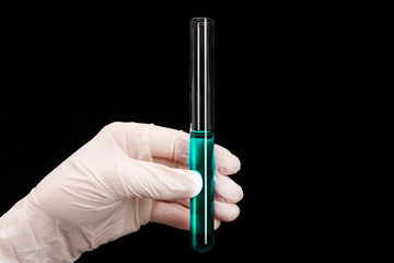 a test tube with a green liquid in hand, a close-up photo on a black background. vaccine development and experiments