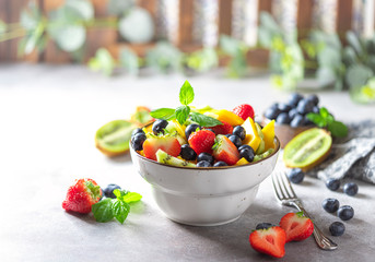 Fresh organic fruit salad on a light concrete background.