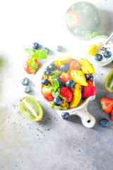 Fresh organic fruit salad on a light concrete background.