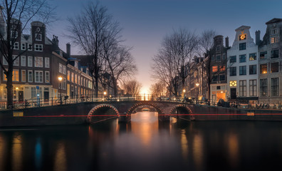 Fototapeta na wymiar View over the Herengracht canal and the Vierheemskinderensluis bridge in Amsterdam on a quiet winter evening, just after sunset