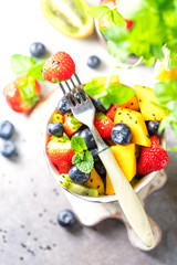 Fresh organic fruit salad on a light concrete background.