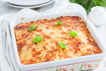 Potato casserole with minced meat in a square ceramic form on a wooden table, selective focus