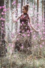 A girl dressed in Japanese style in a flowering forest among pink flowers