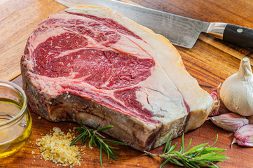 Aged vaca rubia gallega steak, ready to be grilled with garlic, rosemary, salt flakes and extra...