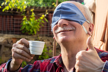 Senior man in protective mask drinking coffee in the garden
